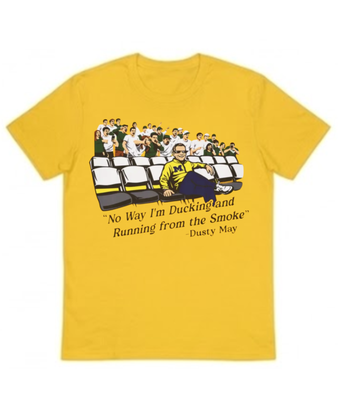 Yellow unisex t-shirt featuring an illustration of coach Dusty May wearing a Michigan sweater, sitting relaxed in stadium seats in front of a crowd, with the quote "No Way I'm Ducking and Running from the Smoke".